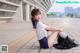 A woman in a school uniform sitting on the ground.