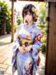 A woman in a blue kimono standing in front of a gate.