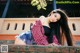 A woman with long black hair leaning against a brick wall.