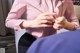 A woman in a pink shirt and black skirt sitting on a couch.