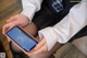 A woman in a school uniform holding a cell phone.