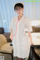 A woman in a white lab coat and glasses posing for a picture.