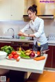 A woman in a kitchen preparing food on a table.