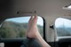 A person's feet sticking out the window of a car.