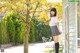 A woman in a school uniform standing next to a tree.