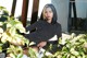 A woman sitting on a bench next to a plant.