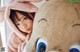 A young girl in a pink bunny costume peeking out from behind a stuffed animal.